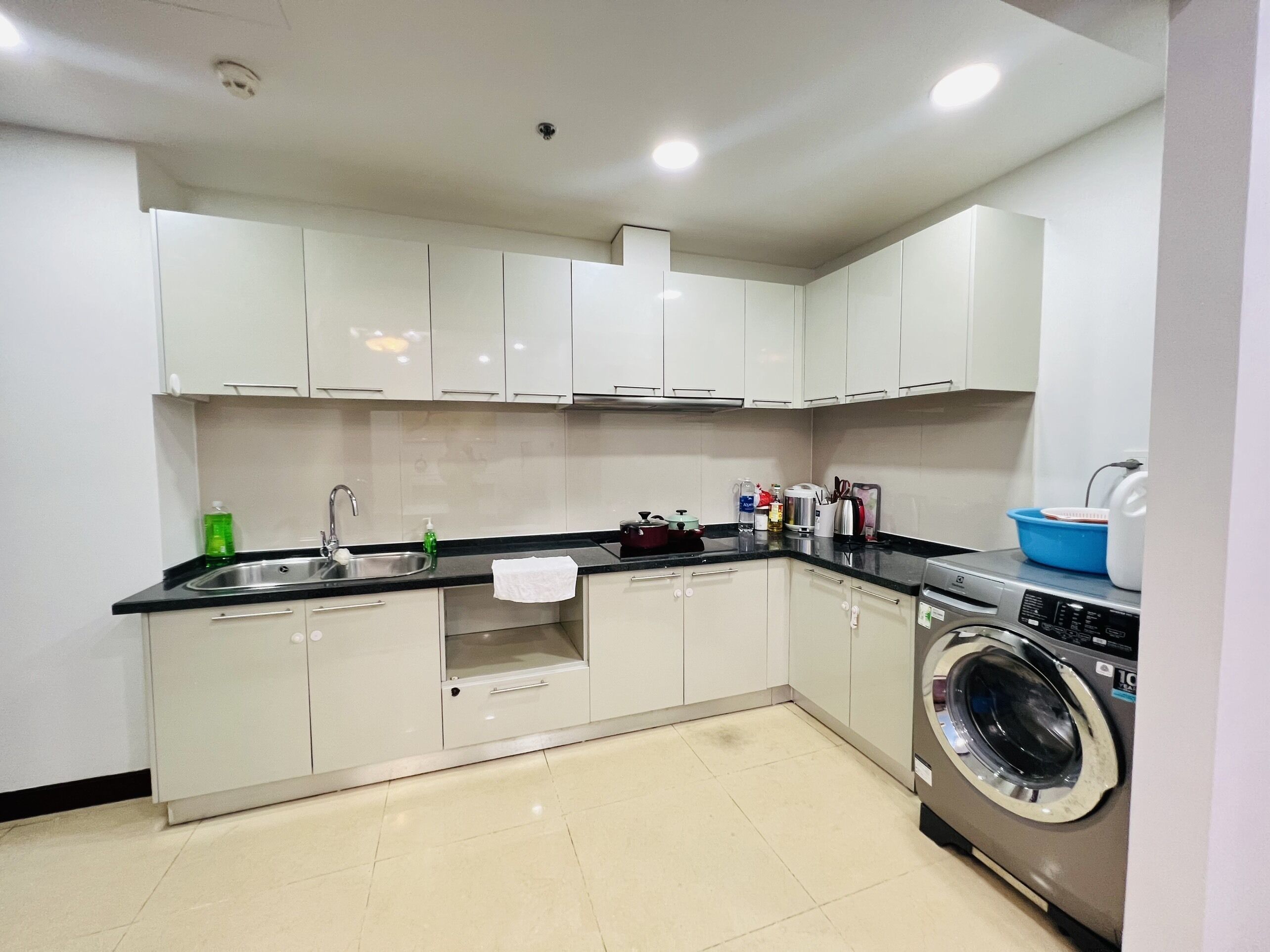 A modern kitchen with white cabinets, a stainless steel sink, and a built-in washing machine.