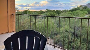 Un balcón con vistas a un paisaje montañoso, una silla y una barandilla.