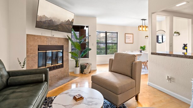 Una sala de estar moderna con chimenea, un televisor de pantalla plana, un comedor y una cocina con encimera.