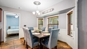 Un coin repas avec une table en bois foncé, six chaises et un lustre.