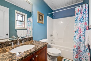 A bathroom with a granite countertop sink, a white toilet, and a bathtub. - Sweet Home Alabama (Foley)
