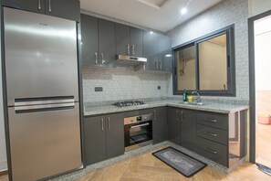 A modern kitchen with a stainless steel refrigerator, a built-in oven, and granite countertops. - NEW Apartment  pravite entry 6 min to the Beach & Downtown Wi-Fi Fiberoptic100MB (Agadir)