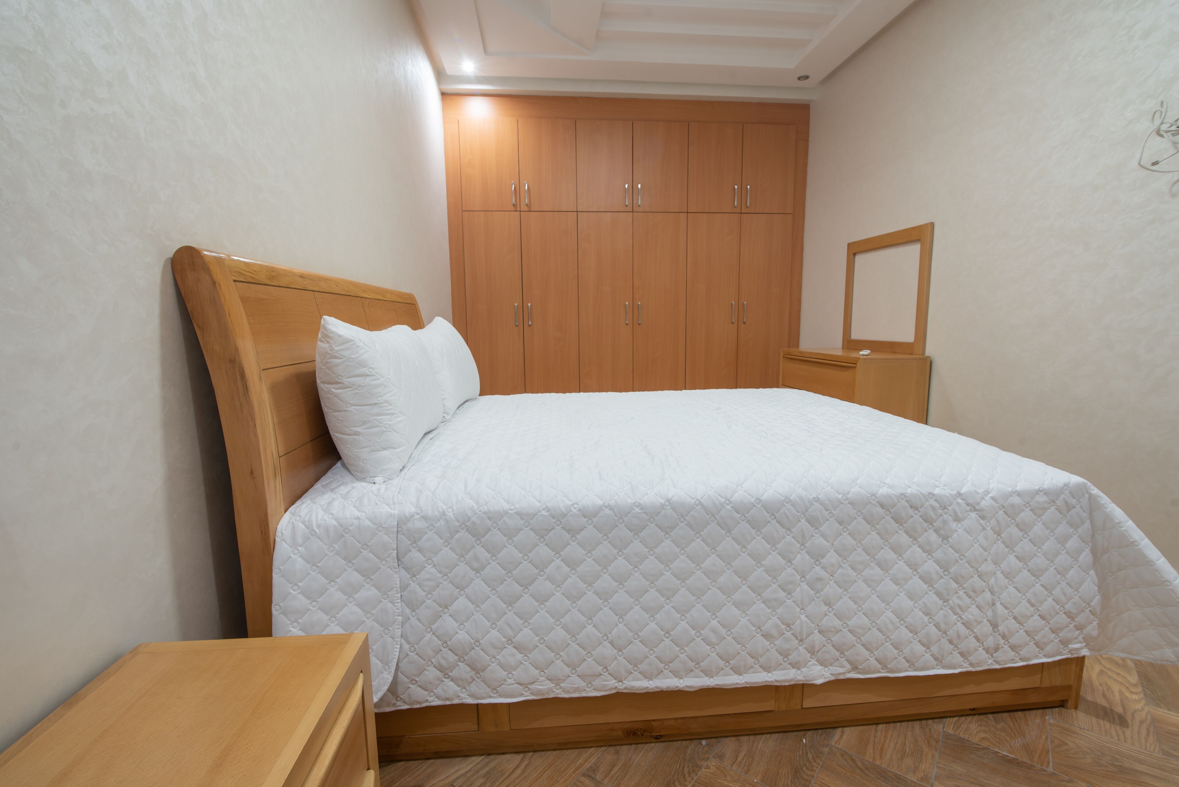 Une chambre à coucher avec un lit en bois, une table de chevet, une armoire et un miroir.