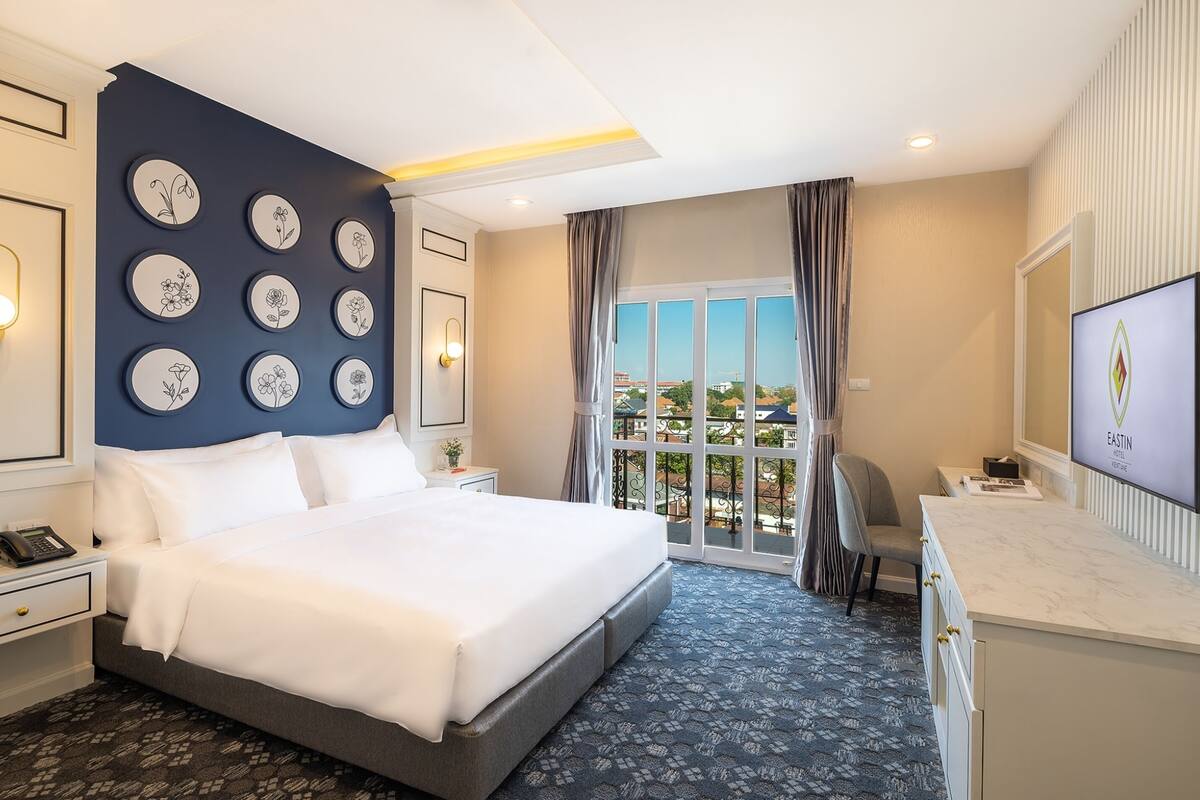 Une chambre d’hôtel avec un grand lit, un bureau, une chaise, une télévision et un balcon avec vue.