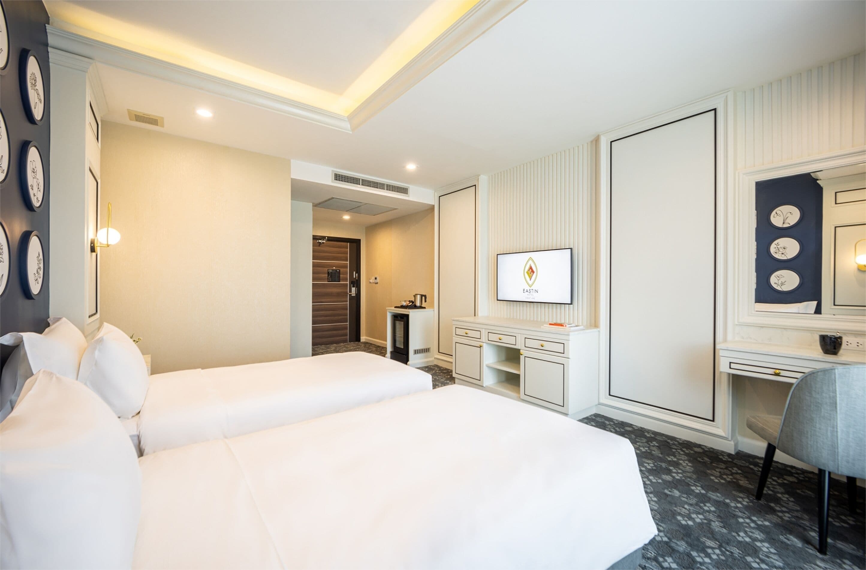 Habitación de hotel con dos camas, un escritorio, una silla, un televisor y un armario.