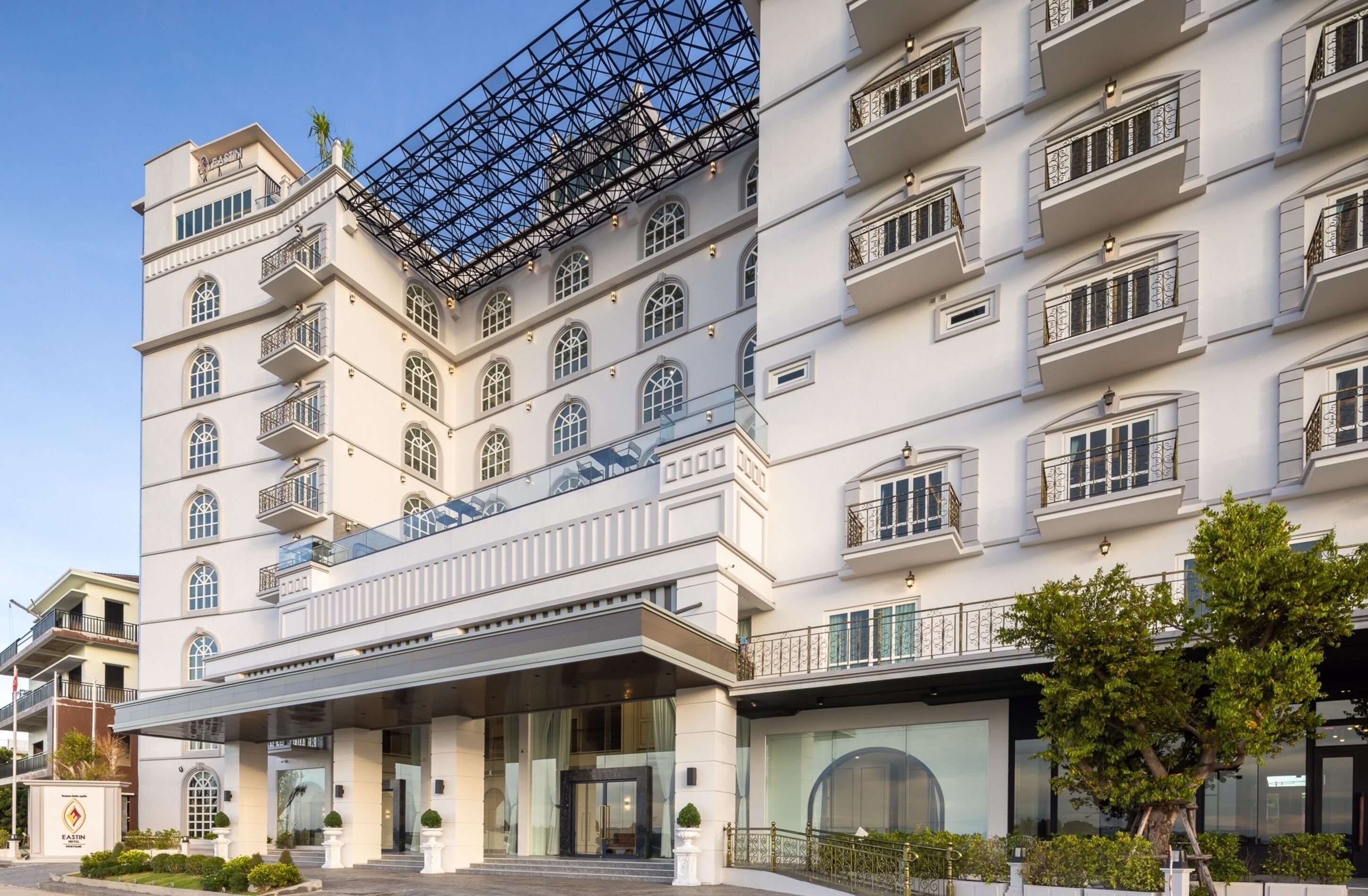 A multi-story hotel with a prominent glass facade, balconies, and a modern entrance.