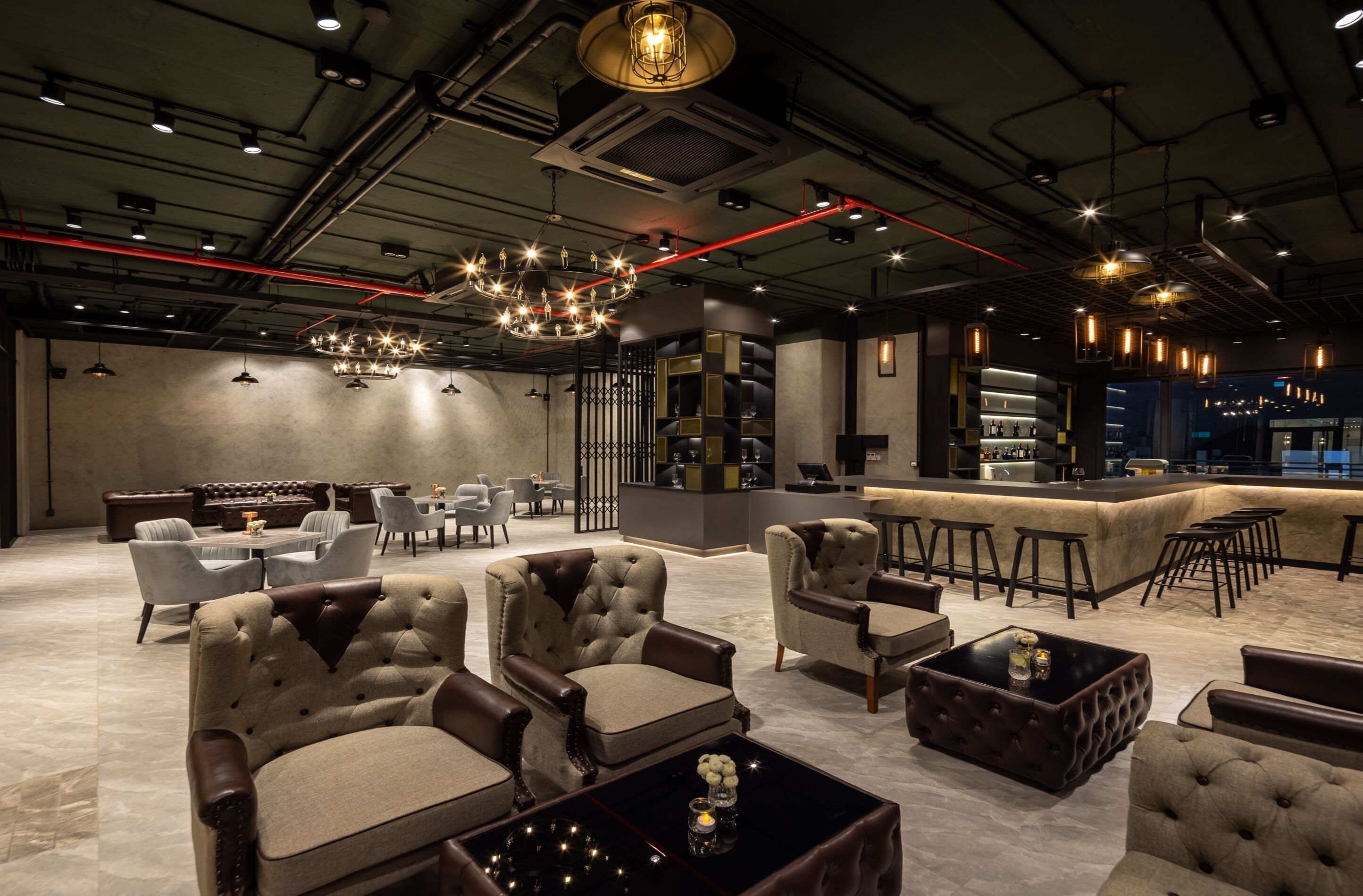 Een moderne lounge met leren banken, een bar en een zithoek met tafels en stoelen.