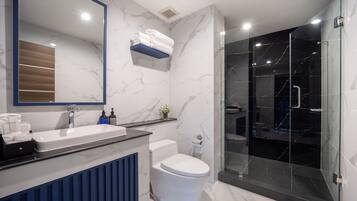 Ein modernes Badezimmer mit Marmorwaschbecken, Toilette und einer Duschkabine.