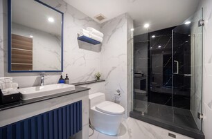Ein modernes Badezimmer mit Marmorwaschbecken, Toilette und einer Duschkabine.