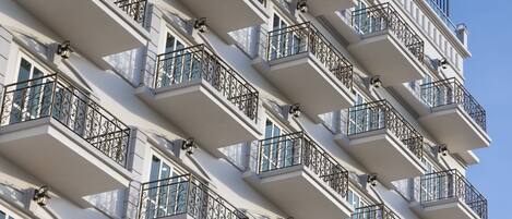A multi-story building with balconies featuring wrought iron railings and windows.