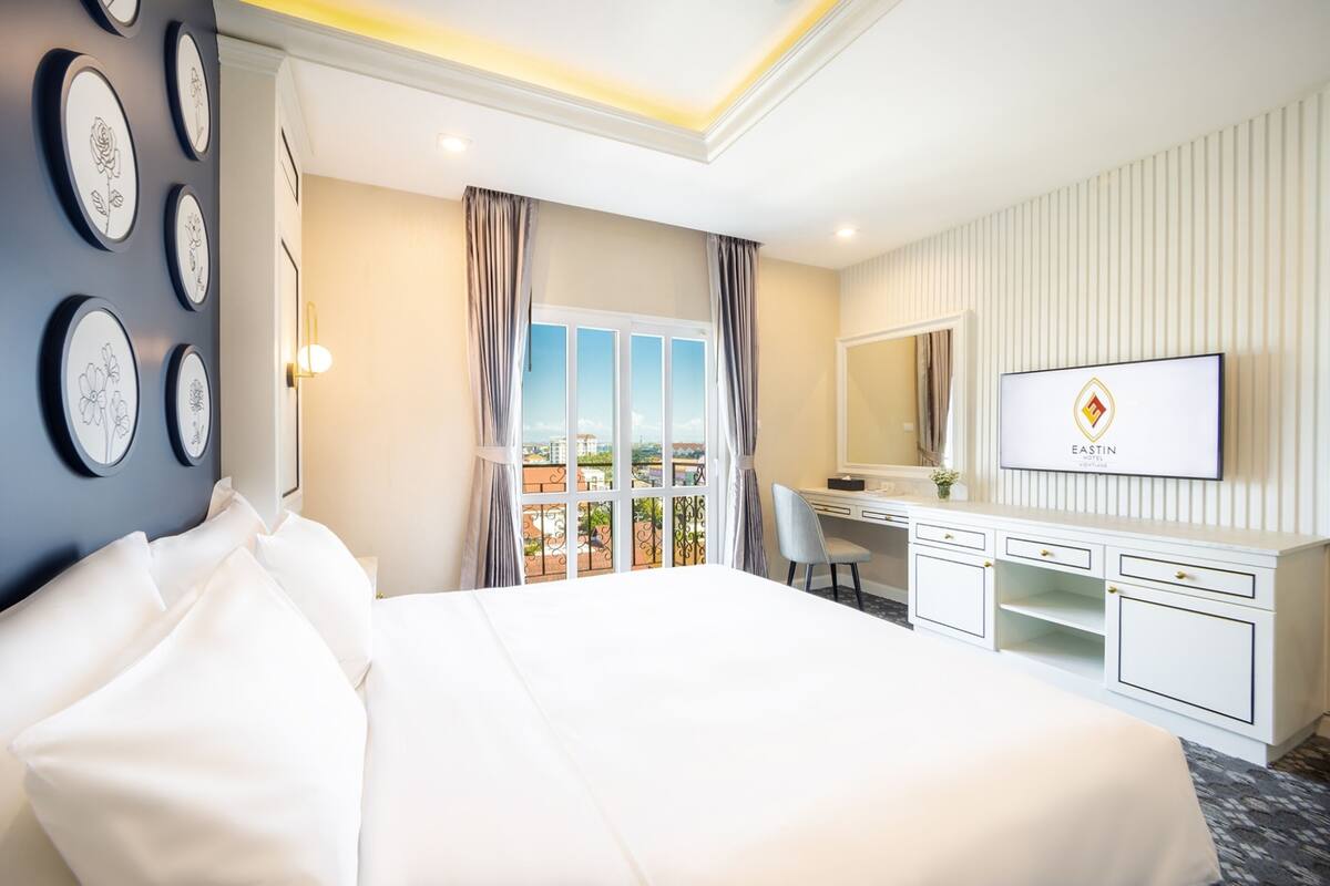Une chambre d’hôtel avec un grand lit, un bureau avec une télévision et un balcon offrant une vue agréable.