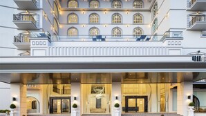 A grand hotel entrance with a covered walkway, large windows, and a well-lit facade.