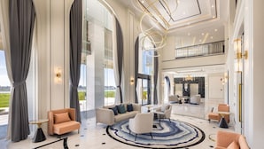 A spacious lobby with a modern design, featuring a large seating area, a round coffee table, and a view of the outdoors.