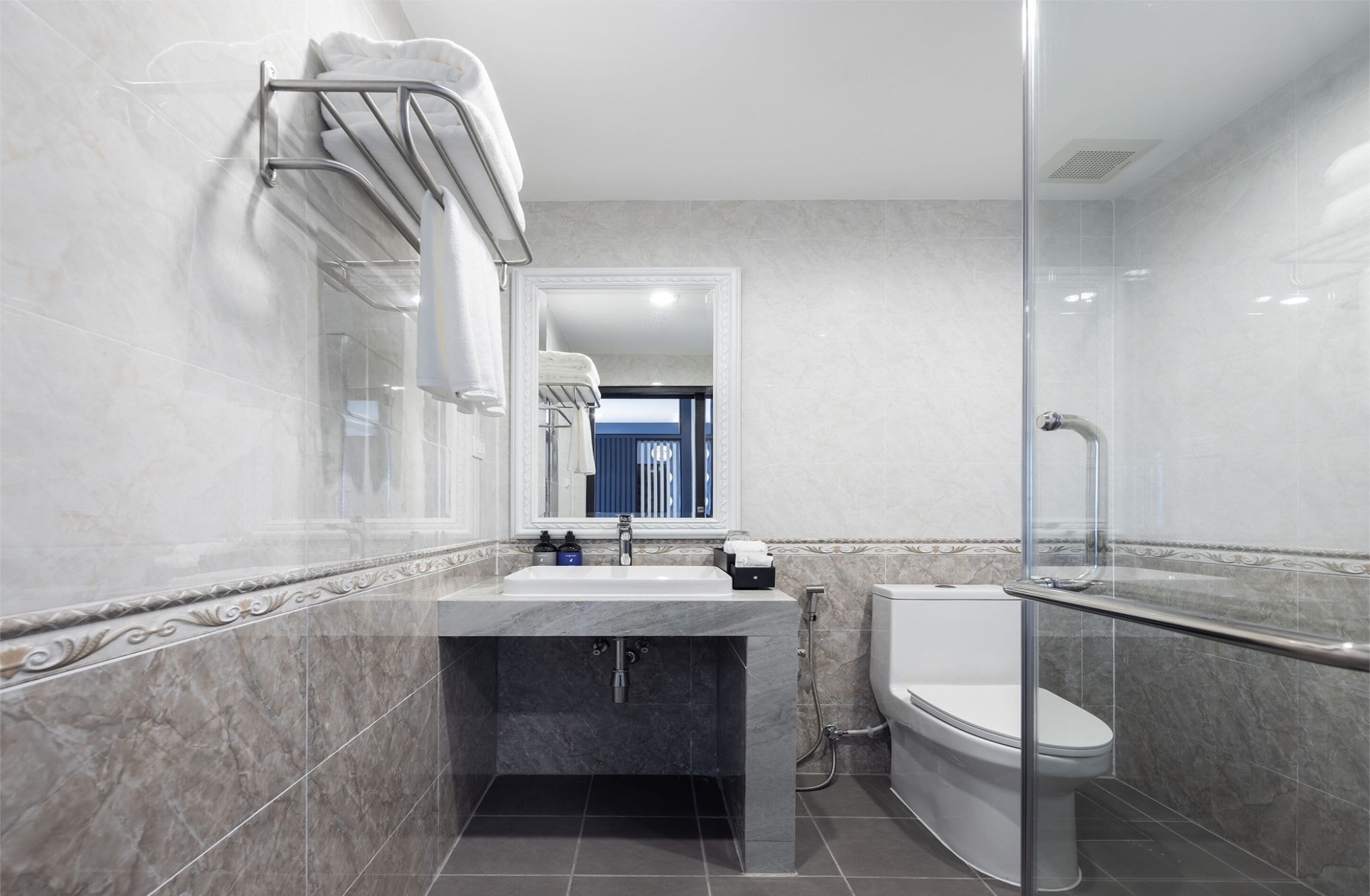 A modern bathroom with a marble sink, a glass shower enclosure, and a toilet.