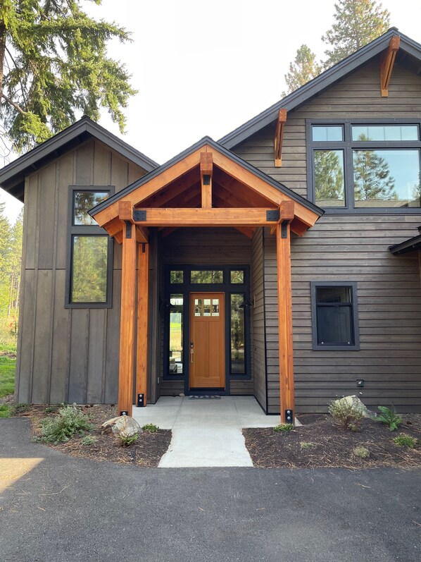 A modern two-story house with a wooden front porch and a dark siding exterior. - Mountain Escape 5BR/5.5BA sleeps 10 w/hot tub on golf course in Suncadia.  (Cle Elum)
