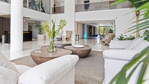 Un vestíbulo amplio con una recepción, zonas de estar y plantas de interior.