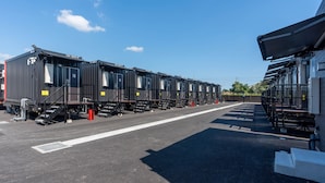 Una fila de vagones de tren negros estacionados en un estacionamiento, con un edificio a la derecha.