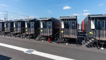 A row of portable cabins with numbered doors, each equipped with a small staircase and a metal railing.