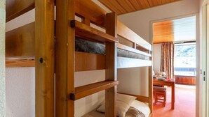 A bunk bed with a wooden frame and a desk with a chair in the room. - Les Tommeuses (Val Claret) by Interhome (Tignes)