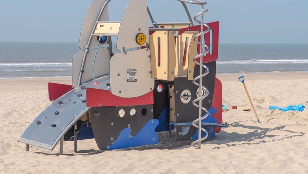 A beachside lifeguard tower with a metal ladder, a red and blue base, and a clear view of the ocean. - Goldsands II 302 with parking by Interhome (De Haan)
