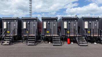 A row of identical shipping containers arranged in a row with metal stairs leading to the doors.