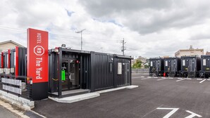 A hotel with a red sign reading "HOTEL The Yard" and a black building with numbered rooms. - HOTEL R9 The Yard Buzen (Buzen)