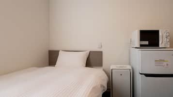 A hotel room with a bed, a microwave, and a refrigerator.