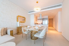 A modern dining area with a long table, white chairs, and a chandelier.