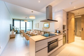 A modern kitchen with a central island, built-in oven, and a large window overlooking a balcony.
