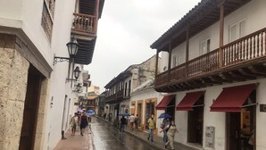 A narrow street with buildings on both sides, some with balconies and awnings.