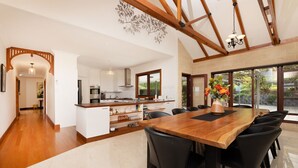 Een moderne keuken met witte kasten, een houten eiland en een eethoek met een grote houten tafel en zwarte stoelen.