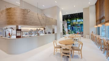 A modern cafe with a wooden counter, round tables, and chairs.
