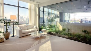 A modern office space with a white sofa, glass coffee table, and potted plants.