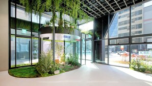 A modern interior with large windows, indoor plants, and a glass wall offering a view of the outside.