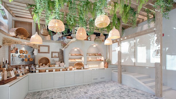 A spacious interior with a stone floor, wooden beams, and hanging baskets.