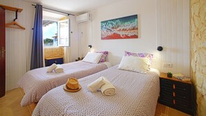 Habitación de hotel con dos camas, un cuadro en la pared, una ventana con cortinas y un aparador de madera.