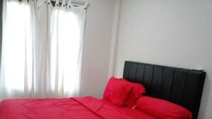 A bed with a black headboard and red bedding. - LEMBUNAI HOME STAY (Labuan Bajo)