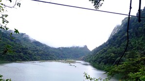 A river surrounded by lush green hills and a bridge overhead.