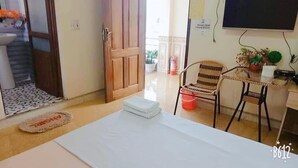 A small room with a bed, a chair, a table, and a TV.