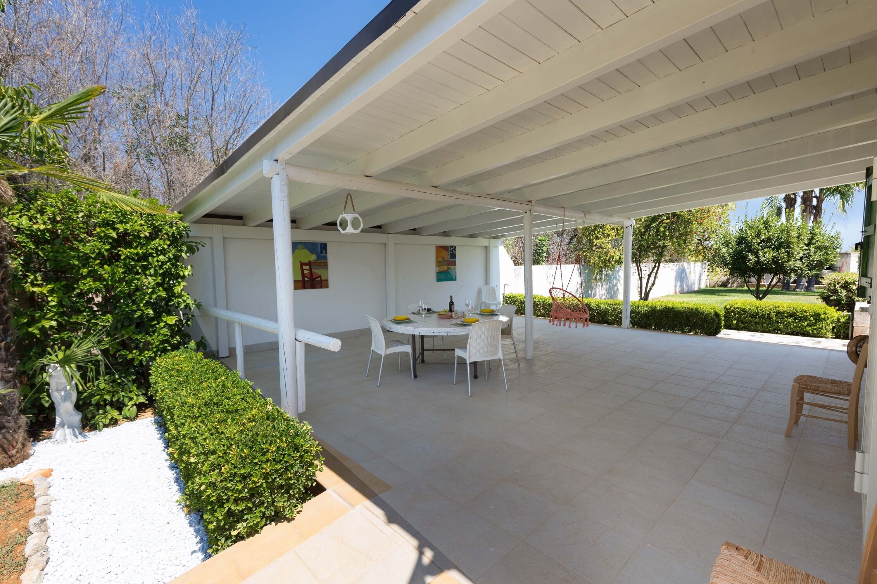 An outdoor patio with a covered seating area, a table with chairs, and a decorative hanging light.