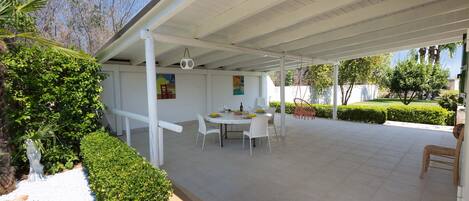 An outdoor patio with a covered seating area, a table with chairs, and a decorative hanging light.