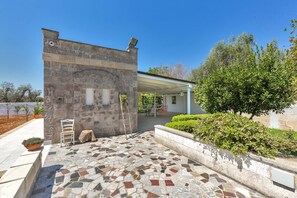 A stone building with a tiled patio, a covered outdoor seating area, and a tree. - 3121 La Cornula by Barbarhouse (Campi Salentina)