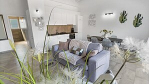 Un salon moderne avec un canapé gris, une table à manger et une cuisine en arrière-plan.