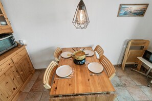 Een houten eettafel gedekt voor vier personen, met een decoratief item in het midden, omringd door houten stoelen.