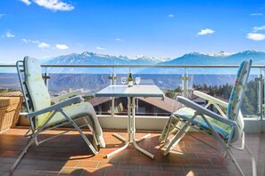 Un balcón con dos sillas y una mesa, con vistas a un paisaje montañoso.