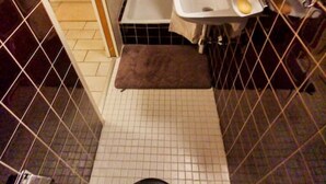 A small, tiled bathroom with a toilet, a sink, and a shower area.
