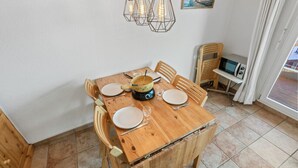 Una mesa de madera para comer dispuesta con platos, cubiertos y una cafetera.