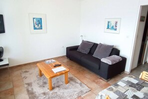 A living room with a black sofa, a wooden coffee table, and two framed pictures on the wall. - Marigny 65 - Beautiful view, ideal for skiing, quiet location (Crans-Montana)