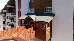 A modern building with a wooden facade and a red awning. - Marigny 45 - Hiking, mountain walks, skiing, quiet location (Crans-Montana)