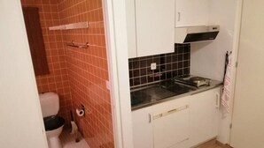 Une cuisine de taille réduite, dotée d’un évier, de meubles blancs et d’un dosseret carrelé.